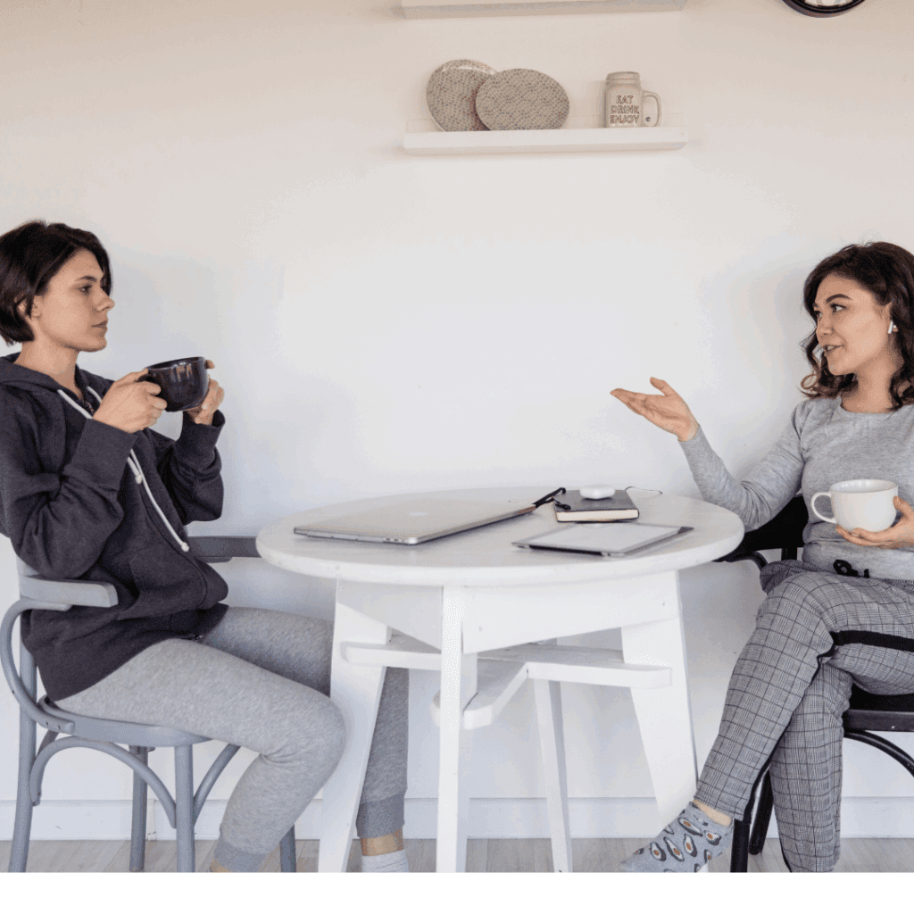 Two women discussing business over coffee, learning which sales phrases to avoid for more confident communication.