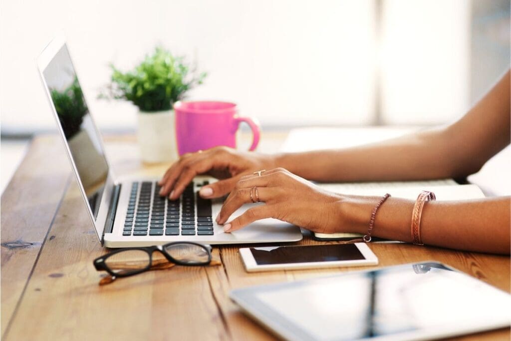 Hands of a woman entrepreneur typing on a laptop, building sales confidence for women through authentic, heart-centered communication.