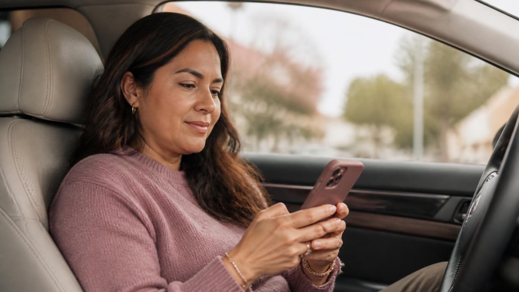 Network marketing leader sitting calmly in her car with phone planning her daily activity